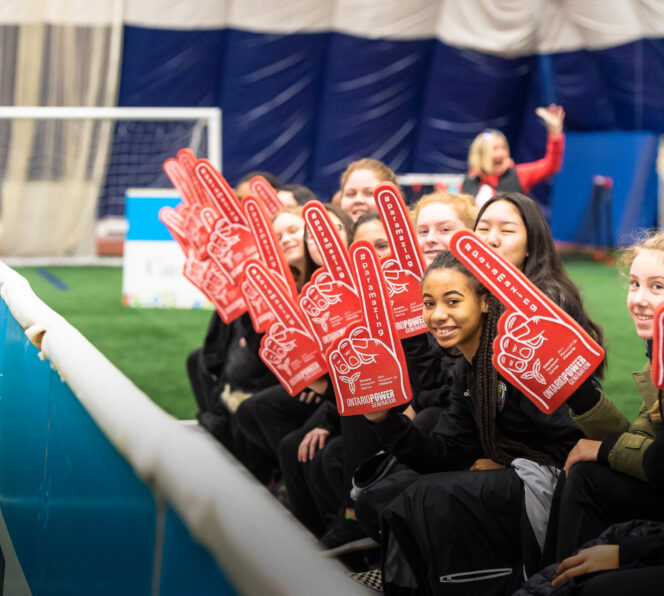 Volunteers sitting in a row holding up a number 1 finger sign that is red and has the words #paramazing on the finger and the Ontario Parasport logo on the palm of the hand.