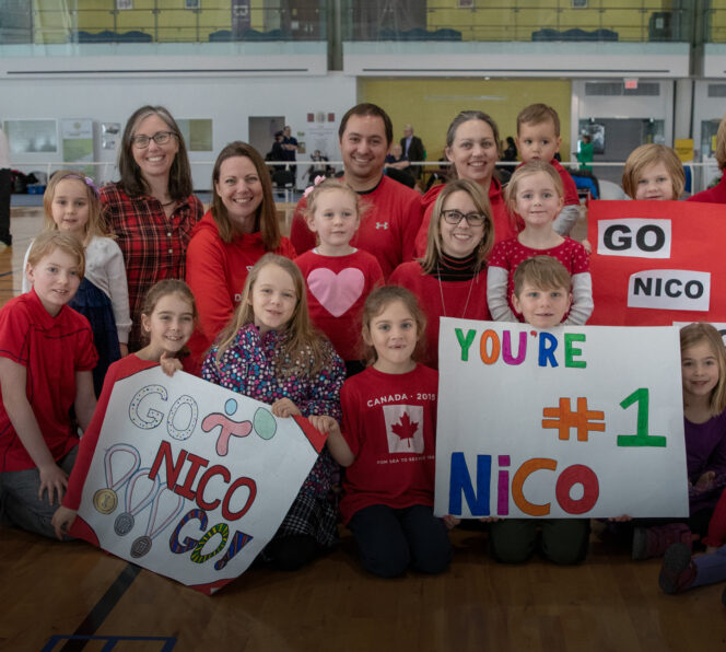 A group of people cheering on an athlete at a game finals.